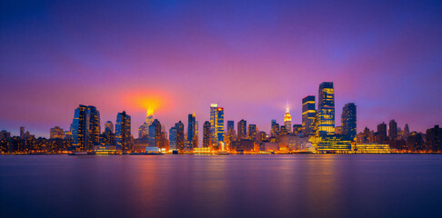 Fototapeta premium Panoramic city skyline view at sunset over calm water with reflection, panorama