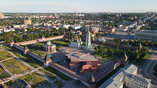 Cinematic aerial panorama of the Tula Kremlin and city center at sunset. Historic brick fortress with ancient towers and the Assumption Cathedral's golden domes under a clear sky in Russia