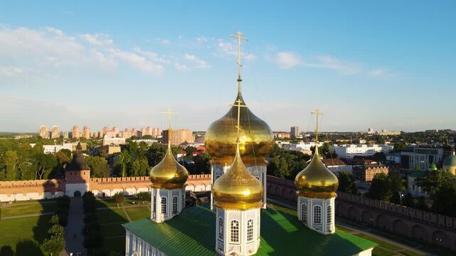 Aerial orbit shot of the majestic golden domes and crosses of the Assumption Cathedral in Tula Kremlin, Russia. Cinematic close-up of Russian Orthodox architecture during a bright sunny day