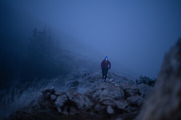 Solo Hiker With Headlamp Trekking a Foggy Mountain Trail at Night in Frosty Winter Conditions © .shock