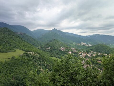 villaggio immerso tra colline e montagne verdi, con case distribuite lungo le valli e un&rsquo;atmosfera naturale e tranquilla tipica dei paesaggi dell&rsquo;Italia centrale
