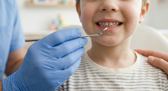 Faceless child smiling during dental checkup with mirror in clinic