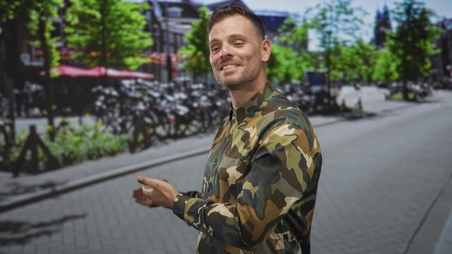 Man in camouflage uniform gesturing with hands on a tree lined city street with parked bicycles and sidewalk; pride duty.