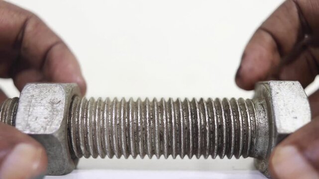 Hand turning a metal nut along the threaded bolt in a smooth cinematic motion sequence
