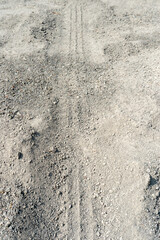 Fototapeta premium Sandy road with small, uneven gravel. Vehicle tire tracks are clearly visible.