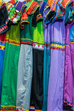 Rows of vibrant Ng&auml;be-Bugl&eacute; Nagua dresses with colorful geometric patterns and intricate woven craftsmanship for display - stock photo