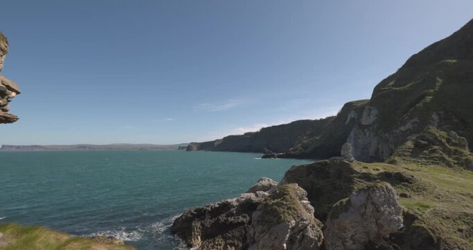 revealing shot of the coastal view from. Kinbane Castle during summer