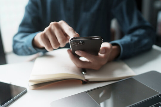 Businessman using mobile phone while working by connecting technology and synchronizing between devices