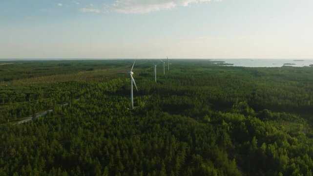 Drone rising toward wind power generators in Hanko nature, summer in Finland