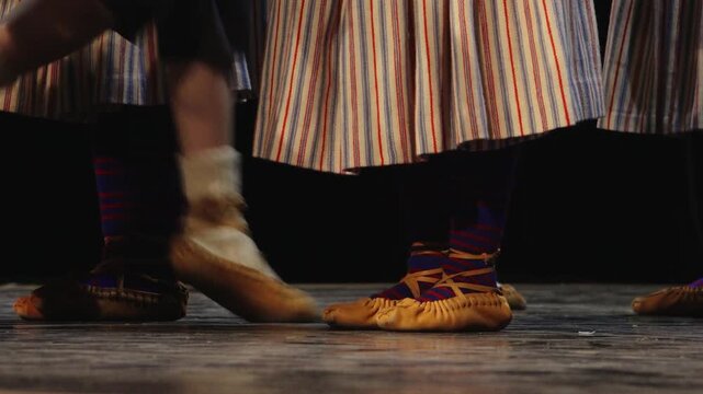 Close-up of dancers' feet in soft leather shoes and white socks performing on a stage, capturing movement, rhythm, and traditional folk dance.