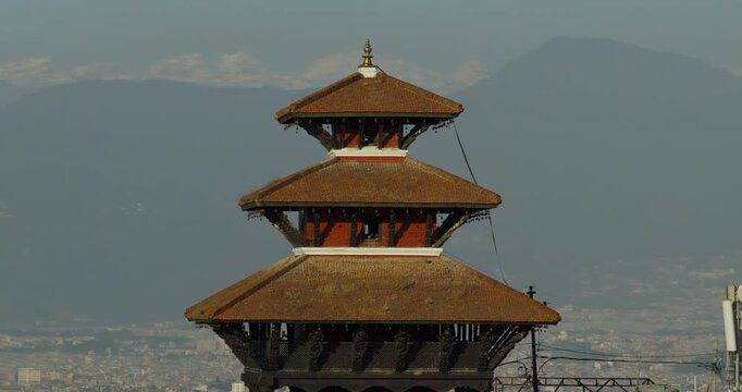 Aerial drone shot of the historic Uma Maheshwar Hindu temple in Kirtipur showing traditional pagoda architecture against the snow capped Himalayan peaks in Kathmandu Valley Nepal.