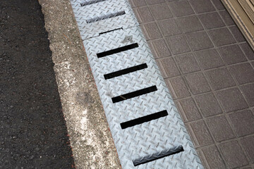 Fototapeta premium Steel drainage grate on sidewalk near shop entrance