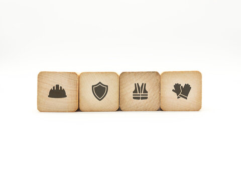 Industrial Safety Equipment and Workplace Protection Icons Concept on Wooden Blocks. Features hard hats, shields, vests, and gloves.