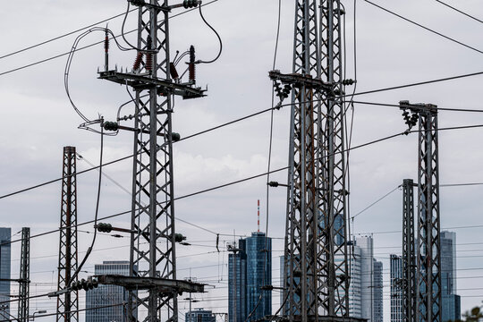 Electric pylons carry wires across an industrial skyline, where transmission towers and utility network infrastructure rise into the sky