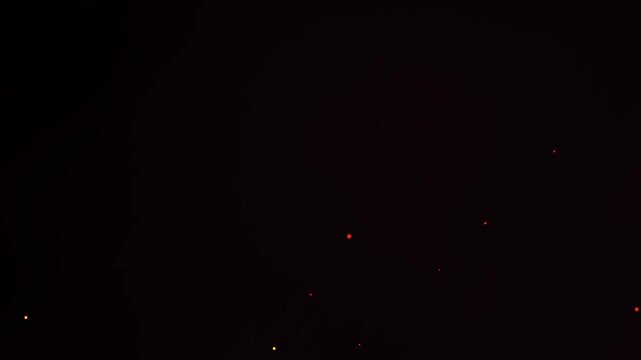 Fire embers particles over black background. Fire sparks background. Abstract dark glitter fire particles lights.