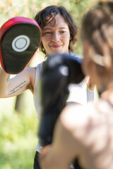 Obraz premium Woman holding boxing pad during outdoor training