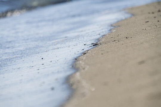 Close-up of gentle waves washing over a sandy beach in Tuscany Italy