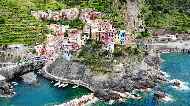 Wide drone panorama of Manarola village, terraced vineyards and turquoise Mediterranean waters, Cinque Terre UNESCO World Heritage site, Ligurian coast, Italy