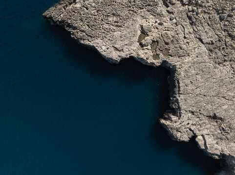Aerial view of the rugged limestone cliffs and deep blue Mediterranean waters of the Plemmirio Marine Protected Area Plemmirio, Sicily, Italy.
