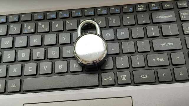 Lock on top of laptop computer keyboard. Tech device privacy, system security and user data safety concern. Cybercrime, cyberattacks, online scams in technology business concept. Closeup rotating view