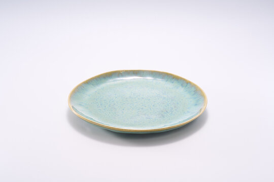 Close-up of flat bottom dinner plate with emerald green sintered ceramic texture on white background