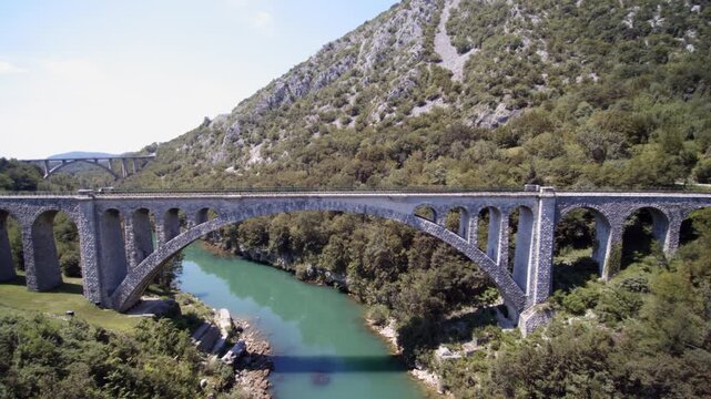 Aerial shot of red train crossing the Solkan Bridge over Soča River near Nova Gorica in western Slovenia.