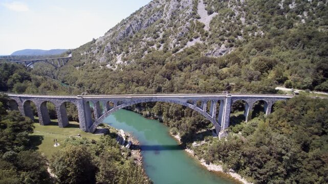 Drone shot of red train crossing the Solkan Bridge over Soča River near Nova Gorica in western Slovenia.