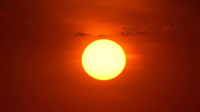 Sun sunset sky featuring a close up of the glowing sun disk against a vibrant orange and red background during dawn