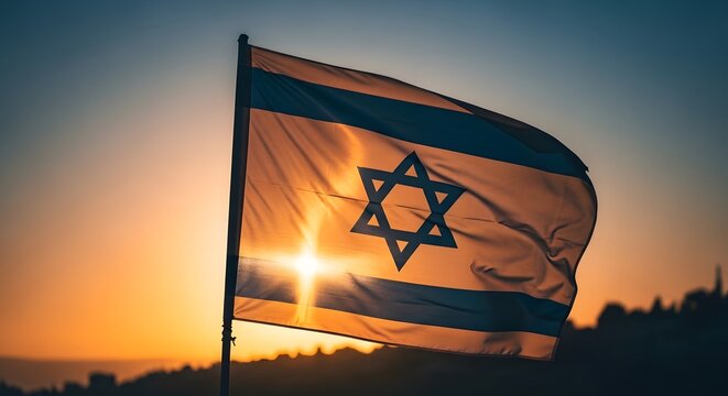 The national flag of Israel waves gracefully against a bright, golden sunset in the clear evening.