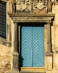 Obraz premium Blue wooden door at historical building during daylight with stone carvings and pillars in close view