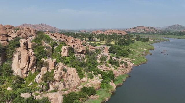 Aerial 4K drone footage of Hampi in Karnataka India. Cinematic bird's eye view of ancient ruins and boulder-strewn landscape along the Tungabhadra river.
