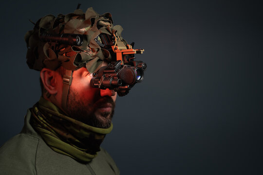 Tactical operator in night vision monocular on dark background with copy space for text