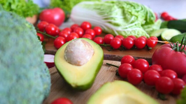 Colorful arrangement of fresh organic vegetables, including a sliced avocado, broccoli, and cherry tomatoes, slowly revealing a rich assortment perfect for a healthy diet and vegetarian meals