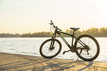 Fototapeta premium A bicycle parked on the riverbank, with sunlight reflecting off the water surface.