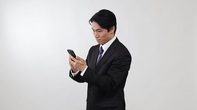 嬉しそうにスマートフォンを操作するビジネスマン