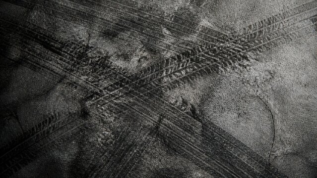 Tire marks on weathered cement floor create an abstract industrial pattern featuring dark rubber skid marks across a gritty vintage concrete texture
