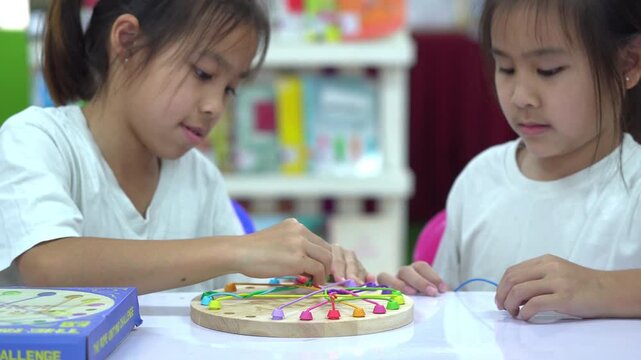 Close up of children's hands playing with a colorful wooden stringing toy, practicing fine motor skills and hand-eye coordination.