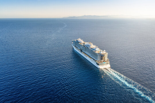 High aerial view of a cruise ship sailing over blue ocean into the sunset with copy space as a concept for travel and vacation