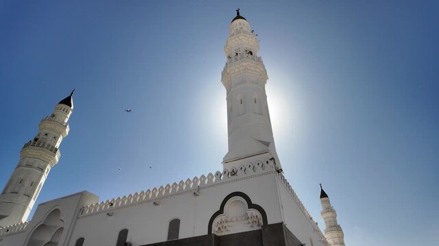 Quba Mosque with bright white domes and minarets under a clear blue sky, a major Islamic landmark and pilgrimage destination in Medina, Saudi Arabia