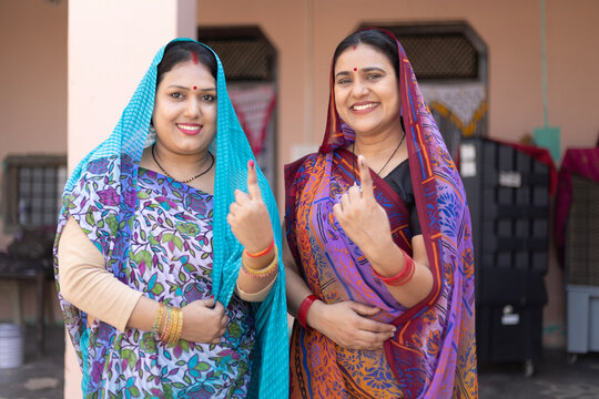 Indian mid aged rural women showing ink marked finger by looking at camera after voting on election - concept of people voting rights, democracy and happiness