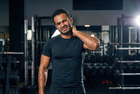 Man experiencing muscle strain and injury in his neck during a fitness session
