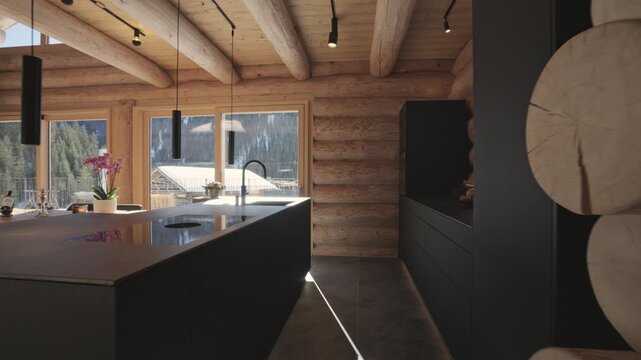 Slow camera movement showing a modern black kitchen inside a luxurious rustic log cabin in the mountains