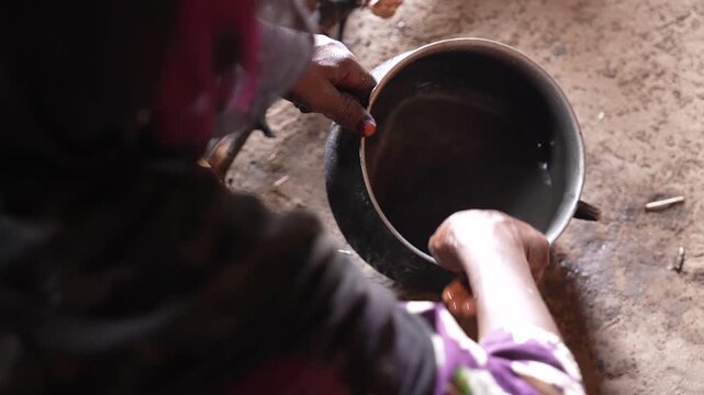 Close up of African woman washing dishes in rustic village kitchen, April 25, 2026, Chad, N Djamena