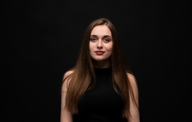 Naklejka premium Young woman portrait with long flowing brown hair looking confident and calm on black background