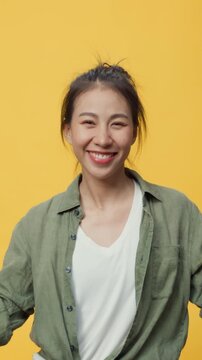 Vertical Screen : Confidence Asia youth lady stand over yellow background open palms points away on copy spac show empty space, presenting advertisement smiling excited. Mock up copy space concept.
