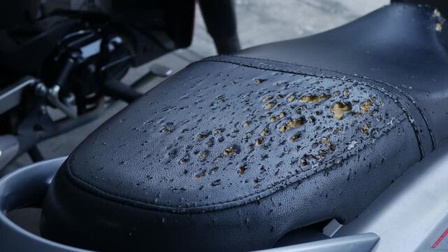 Closeup worn deteriorated motorcycle seat with cracked torn black vinyl exposing orange foam decay texture urban abandoned