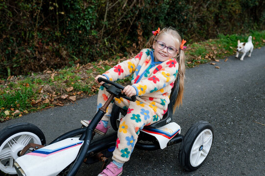 Girl with ponytails riding a toy car