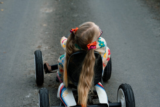 Girl with ponytails riding a toy car