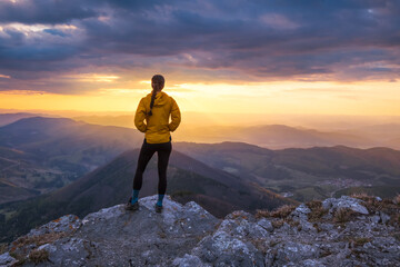 Obraz premium Woman standing on top of a mountain at sunset