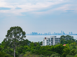 Obraz premium Scenic city skyline across tranquil water with lush greenery foreground, perfect background or screensaver with copy space.